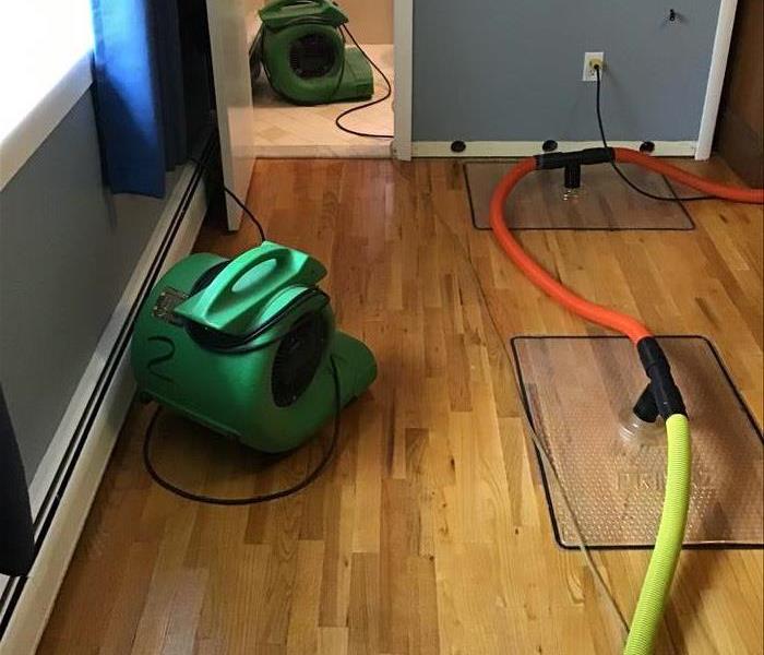 Wood floor being dried with SERVPRO machines.
