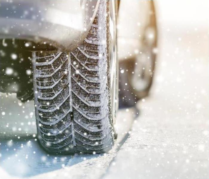 A close-up image of a car and tire moving through snow