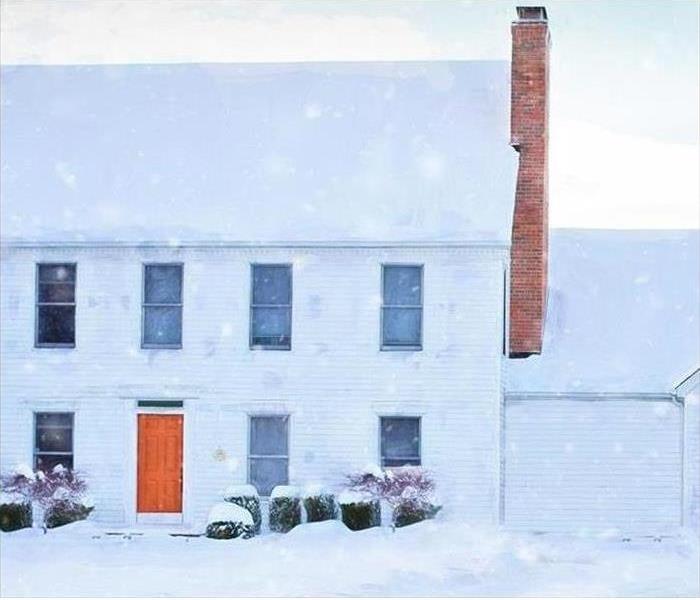 Picture of a white house with an orange door in a snow storm.